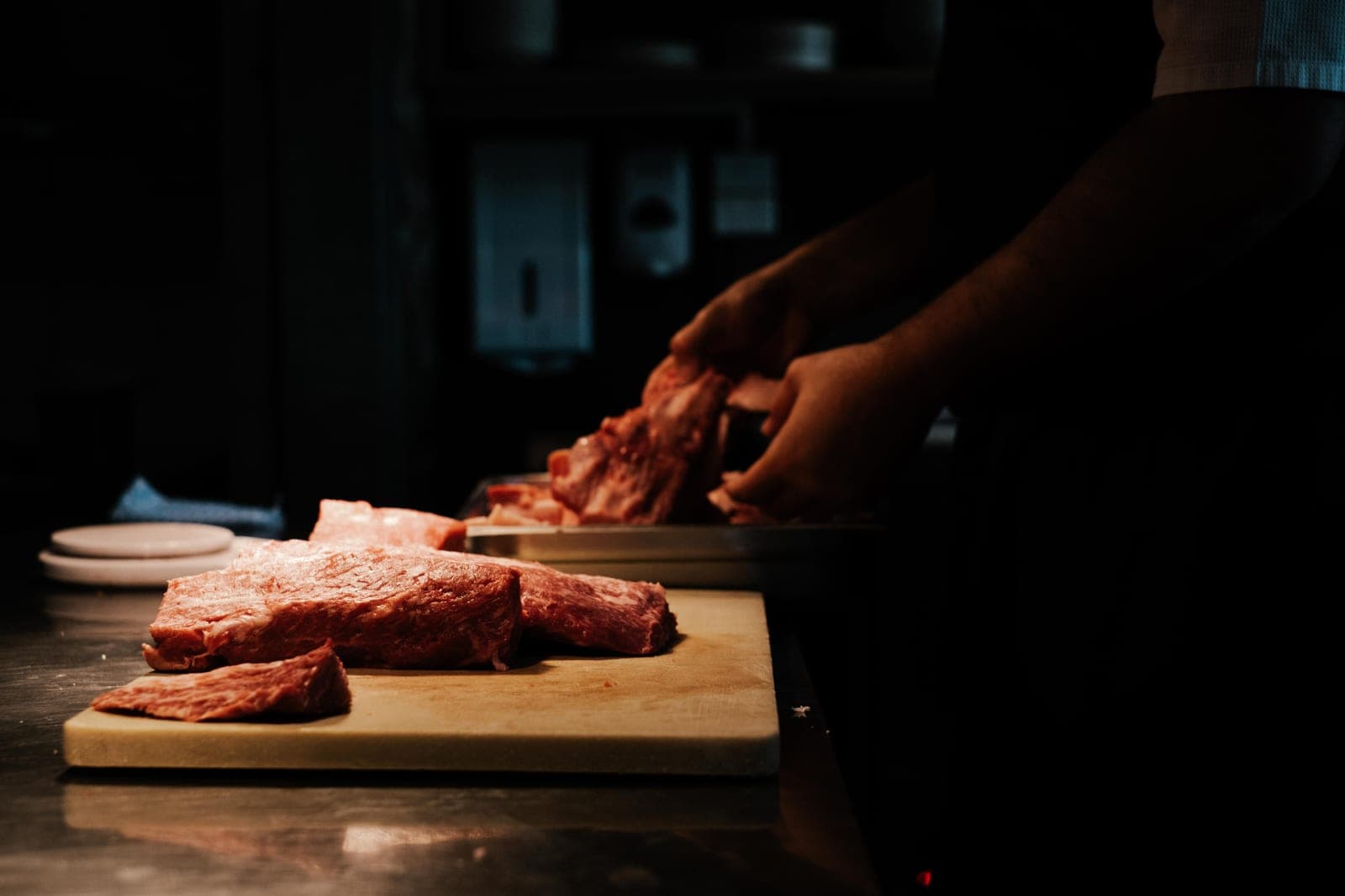 Cutting raw meat on a wooden board in a dim kitchen