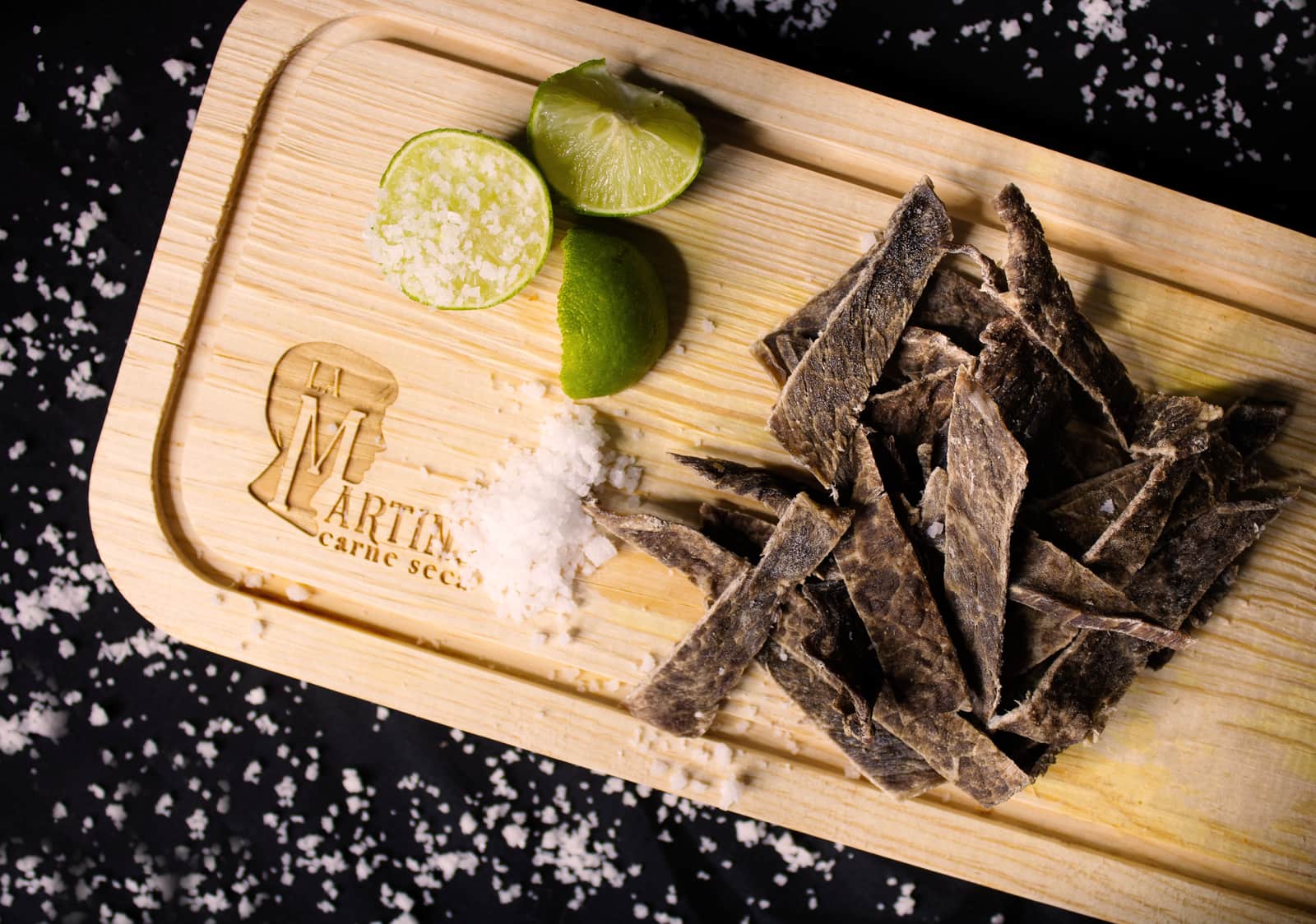 Strips of dried meat on a wooden board with lime and sea salt